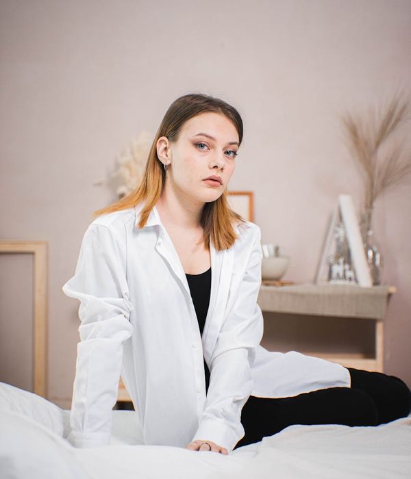 Woman in a calm, focused pose in a bright, minimalist room.